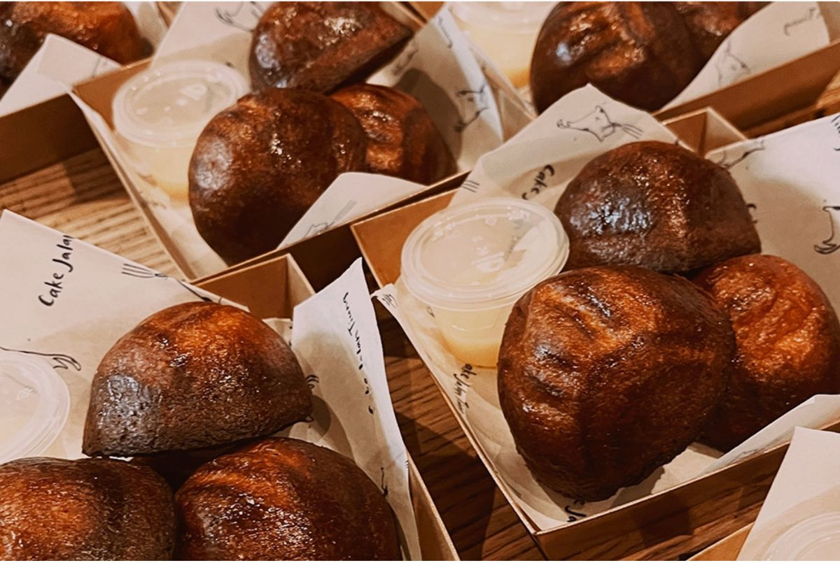 Dark, caramelised butter tteok cakes in paper wrappers, packed in boxes