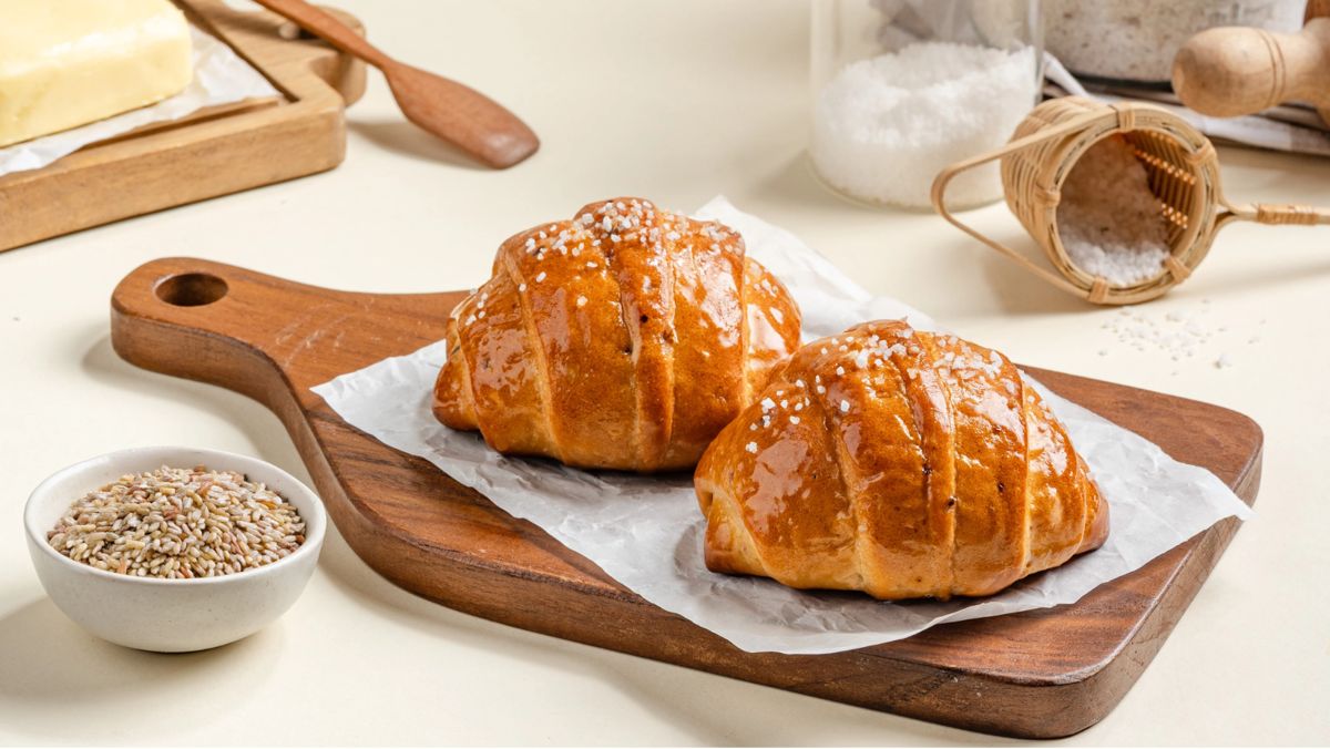 Two glossy shio butter salt-bread rolls on a wooden board
